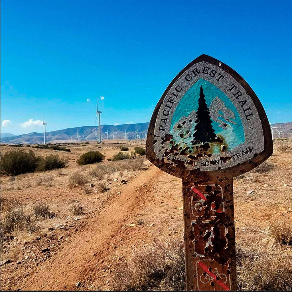 A bullet-riddled sign marks the Pacific Crest Trail at a wind farm near Tehachapi. (Photo Devin Boyd)