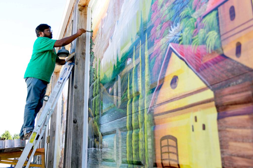 Haider Ali paints the garage doors of Garden Treasures Nursery & Organic Farm in Arlington on Aug. 7, 2018. (Kevin Clark / The Herald)