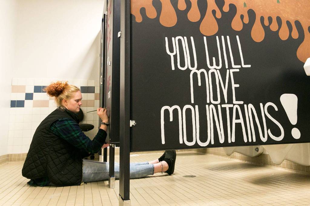 Madison Smith paints a stall in the girls room at Crossroads High School in Granite Falls on Sept. 11. (Kevin Clark / The Herald)