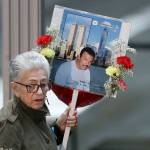 A woman arrives on Tuesday in New York, at the 17th anniversary of the terrorist attacks on the United States, with a sign bearing photo memories for Wilder Gomez. Gomez, from Colombia, was a bartender at Windows on the World on the 103rd floor of the World Trade Center when it was attacked. (AP Photo/Mark Lennihan)