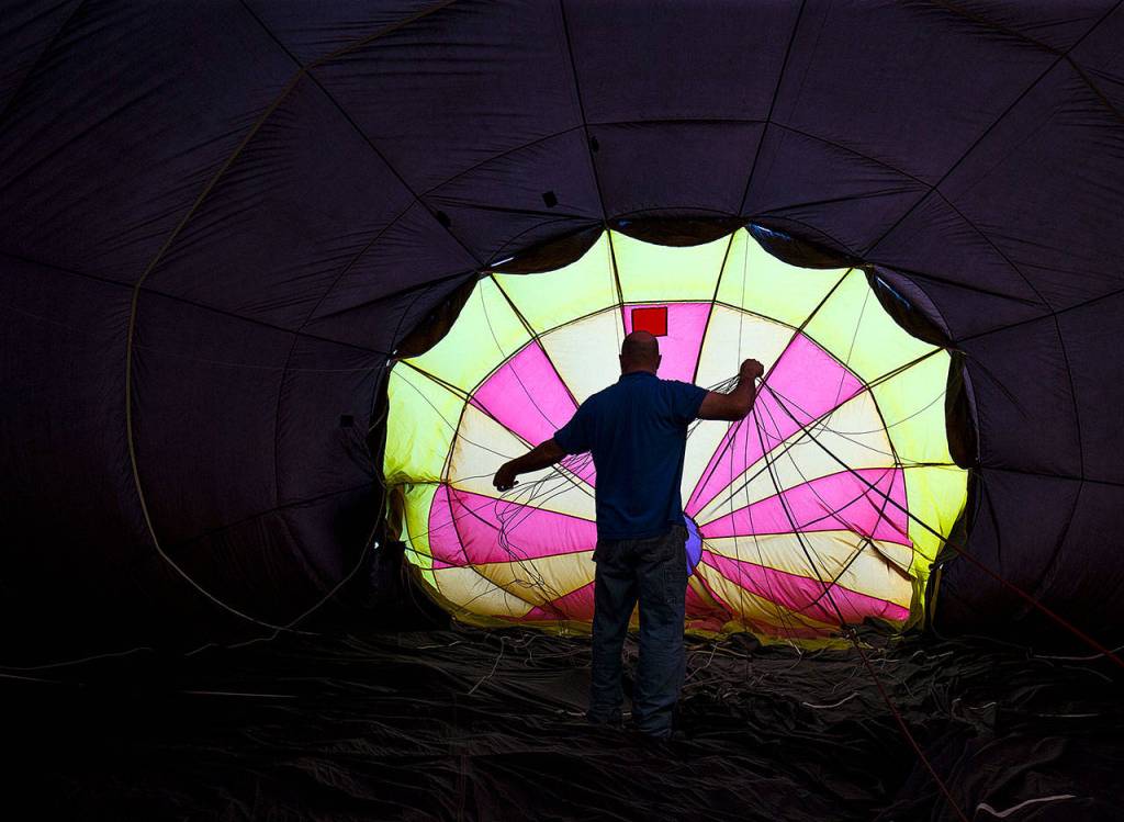 As the balloon fills, pilot Jay Woodward, owner of Balloon Depot, straightens lines inside his hot air balloon. Licensed by the Federal Aviation Administration, Woodward has been piloting hot air balloons for 20 years. (Andy Bronson / The Herald)