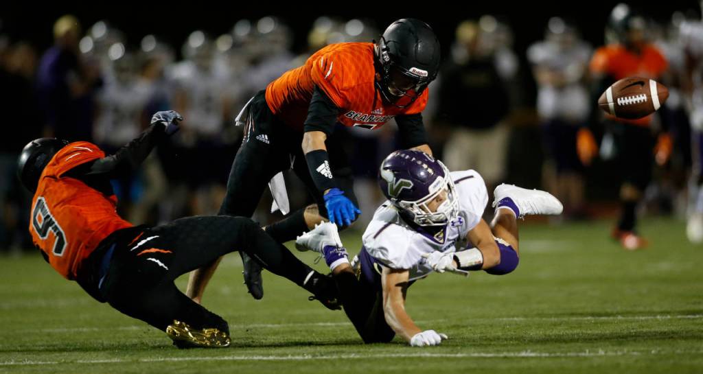 Two Monroe players break up a pass intended for Lake Stevens Ian Hanson during Friday nights game in Monroe. (Andy Bronson / The Herald)