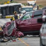 A Snohomish County firefighter stands next to a vehicle involved in a crash on I-5 southbound north of the Highway 530 interchange Sunday in Arlington. (Olivia Vanni / The Herald)