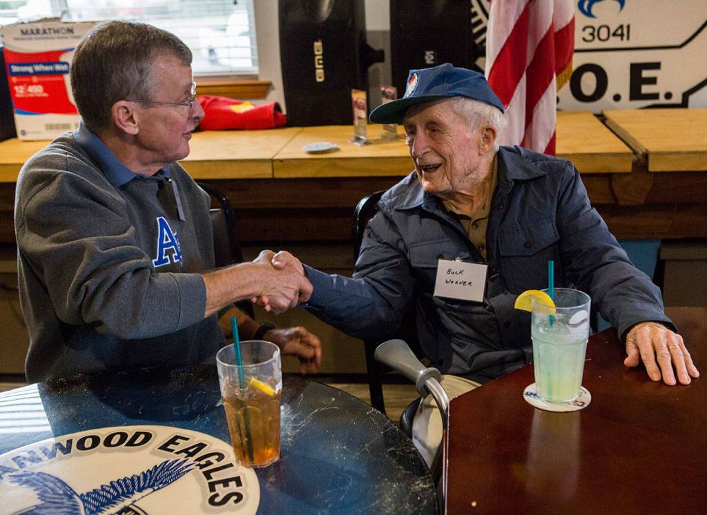 World War II veteran Buck Weaver, 100 (right), shakes Charlie Syllings hand at the Stanwood Fraternal Order of Eagles post Thursday. (Olivia Vanni / The Herald)