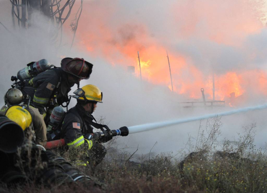 Everett firefighters assist Snohomish County Fire District 4 at a fire that destroyed a large out building on Fobes Road west of Snohomish on Monday. (Doug Ramsay for The Herald)