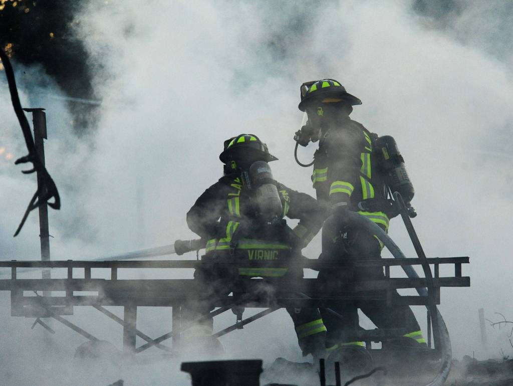 A couple of firefighter from Lake Stevens work to extinquish a fire that destroyed a large outbuilding on the Fobes Road west of Snohomish on Monday night. (Doug Ramsay for The Herald)