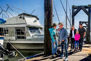 The Taisey family steps out of their little house on the water (left) to walk down the Everett Marina pier to nearby Boxcar Park. From left, they are Joy, 11, Arianna, 10, Caleb, 4, Jacy, Felicity, 7, Ryan and Trusty the dog. (Dan Bates / The Herald)