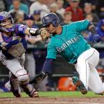 The Mariners Jean Segura (right) avoids a tag by Rangers catcher Robinson Chirinos while sliding safely home in the second inning of a game Sept. 28, 2018, in Seattle. (AP Photo/Elaine Thompson)