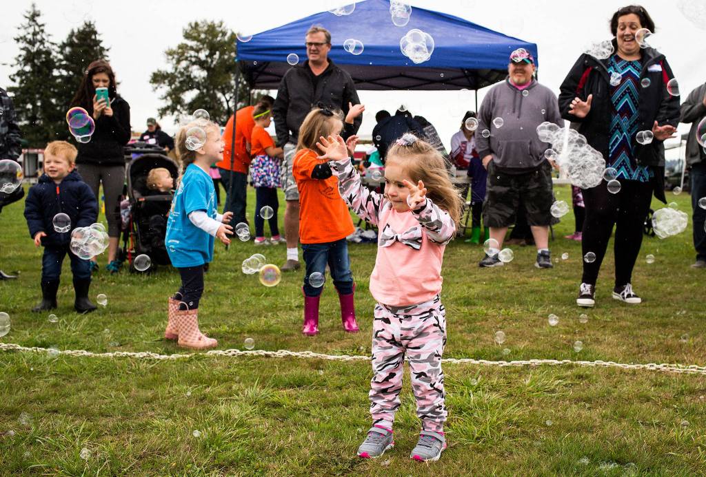 Addison Layton, 3, tries to catch bubbles at the annual Friendship Festival at Harvey Field on Sept. 15 in Snohomish. The event was put on by the Down Syndrome Association of Snohomish County. (Andy Bronson / The Herald)