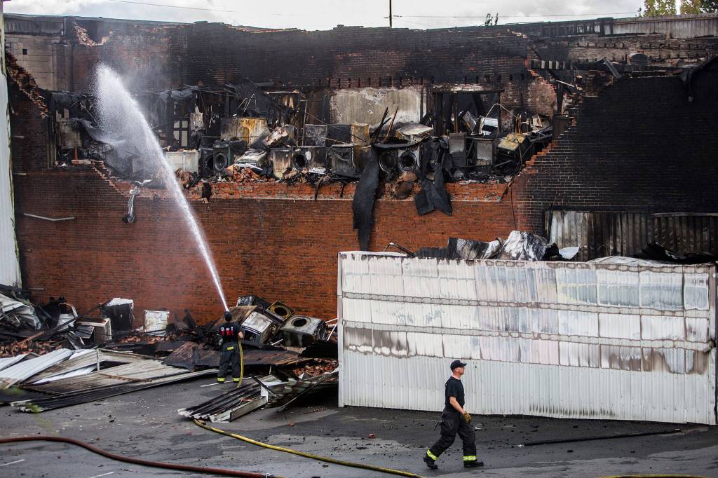 Everett firefighters spray water on the still smoking Judd & Black appliance store at 3001 Hewitt Ave on Sept. 22 in Everett. (Olivia Vanni / The Herald)