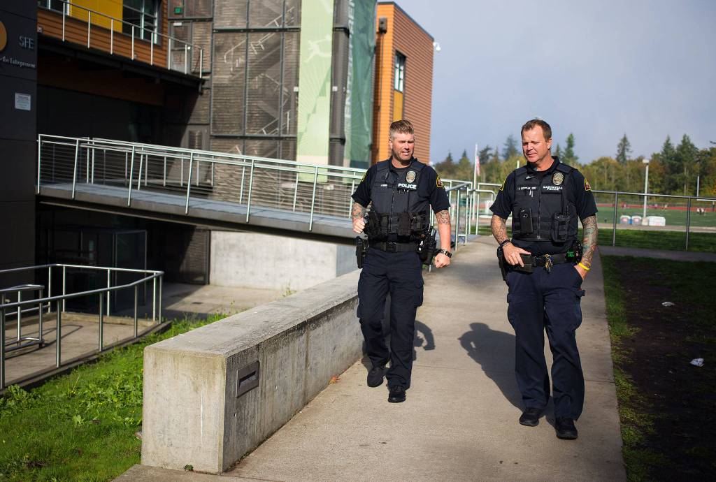 At Marysville Getchell High, School Resource Officers Chris Sutherland (right) and Jeremy Wood talk briefly before Sutherland heads back to Marysville Pilchuck High on Thursday. (Andy Bronson / The Herald)