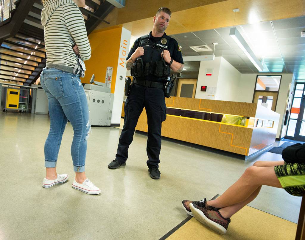 Marysville Getchell High School Resource Officer Jeremy Wood talks with a teacher and student who had been reported missing but was in school, on Thursday in Marysville. (Andy Bronson / The Herald)