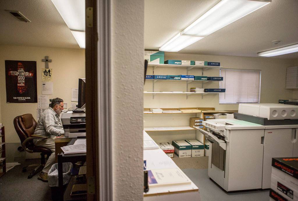Woode Brinkerhoff sits in his office next to the Sonshine Societys printer on Sept. 26, 2018 in Everett, Wa. (Olivia Vanni / The Herald)