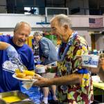 Tim Taylor (far left) serves corn on the cob to Jim Pauley at the Mukilteo Boys & Girls Club on Saturday during the 49th annual Luau & Auction in Mukilteo. (Kevin Clark / The Herald)