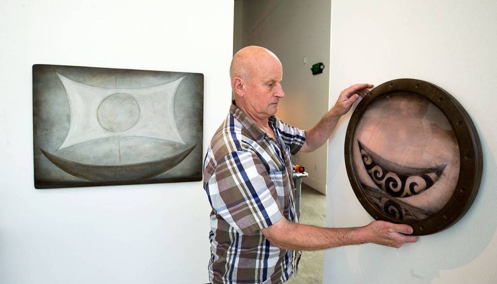 Jensen hangs one of his pieces for his exhibit Voyager at the Schack Art Center in Everett. (Andy Bronson / The Herald)