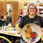 Tina Beard, who is selling her longtime business, Art Escape, shows off one of the many pieces she painted over the years. (Patricia Guthrie / Whidbey News Group)