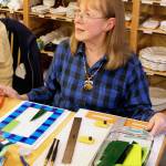Reece Rose chose to learn how to fuse glass at Whidbey Art Escape where she gathers with other women on Wednesday nights. Here she pieces together the pattern that will be put in a kiln. (Patricia Guthrie / Whidbey News Group)