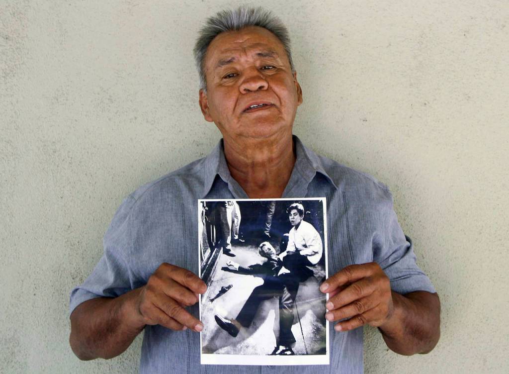 Juan Romero holds a Los Angeles Times photograph that shows Romero with Sen. Robert F. Kennedy at the Ambassador hotel in Los Angeles moments after Kennedy was shot. (Jud Esty-Kendall/STORYCORPS via AP, file)