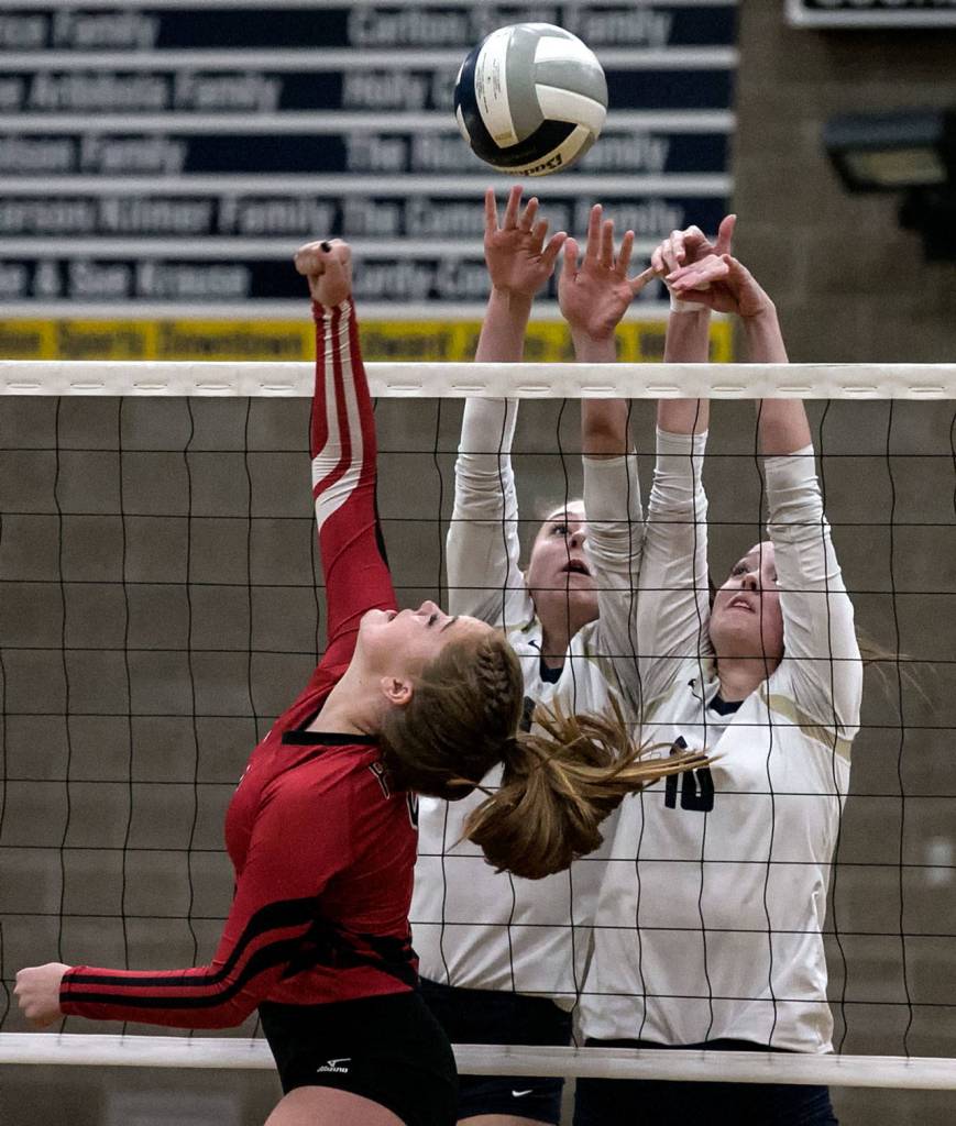 Snohomishs Allison Graham attempts a volley over Arlingtons Sarah Mekelburg and Reese Talbot Thursday night at Arlington High School on October 4, 2018. (Kevin Clark / The Herald)
