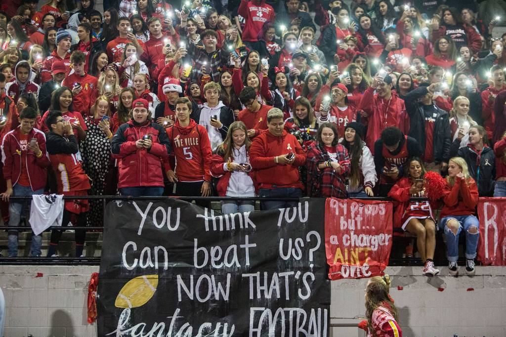 The Marysville Pilchuck student section waves their cellphone lights while they chant the Na Na Hey Hey Kiss Him Goodbye lyrics to the Marysville-Getchell fans at the end of the game on Oct. 5 in Marysville. (Olivia Vanni / The Herald)