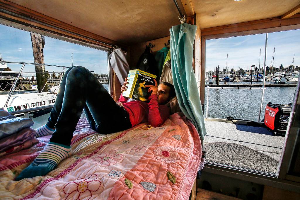On her cozy bed overlooking the Everett Marina, the Everett Yacht Club and boats of all kinds, Arianna reads a Nancy Drew book, The Mystery at Lilac Inn. (Dan Bates / The Herald)