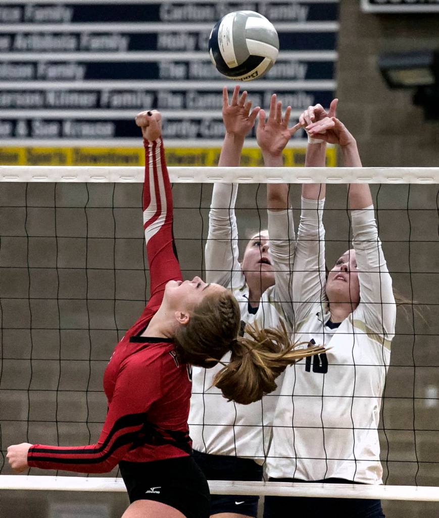 Snohomishs Allison Graham attempts a volley over Arlingtons Sarah Mekelburg and Reese Talbot Thursday night at Arlington High School on October 4, 2018. (Kevin Clark / The Herald)