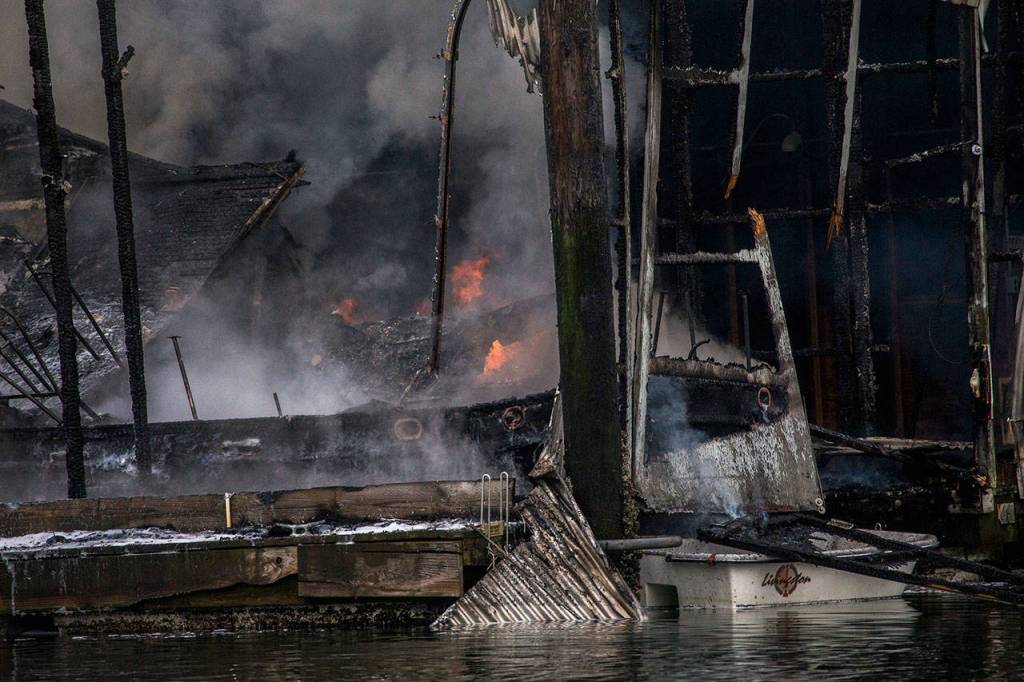 Flames are reignited on a boat that burned in a fire Oct. 8, at the Port of Everett marina. (Olivia Vanni / The Herald)
