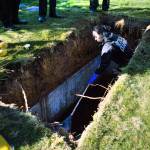 Lauren Higashino, a pathology assistant with the Snohomish County Medical Examiners Office, rakes through water for any left over remains during an exhumation at Cypress Lawn cemetery on Oct. 17, 2018 in Everett. (Olivia Vanni / The Herald)