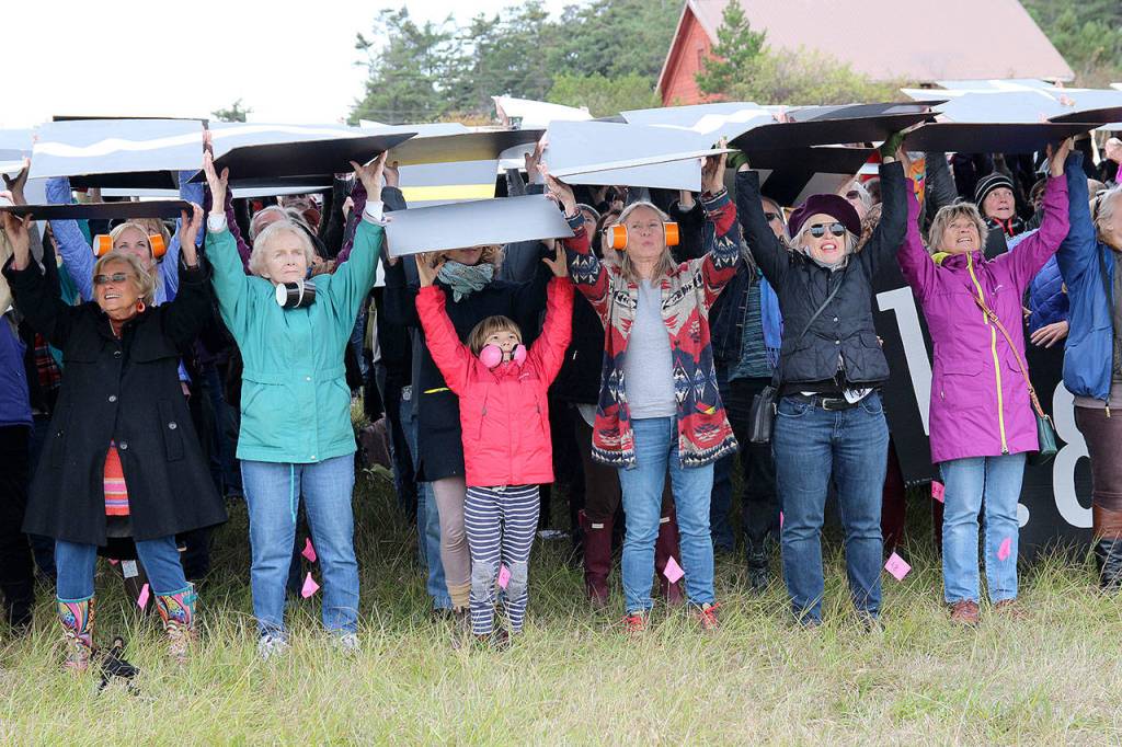 Jessie Stensland / Whidbey News-Times                                 The crowd holds up the cardsat the Oct. 3 rally in Central Whidbey.