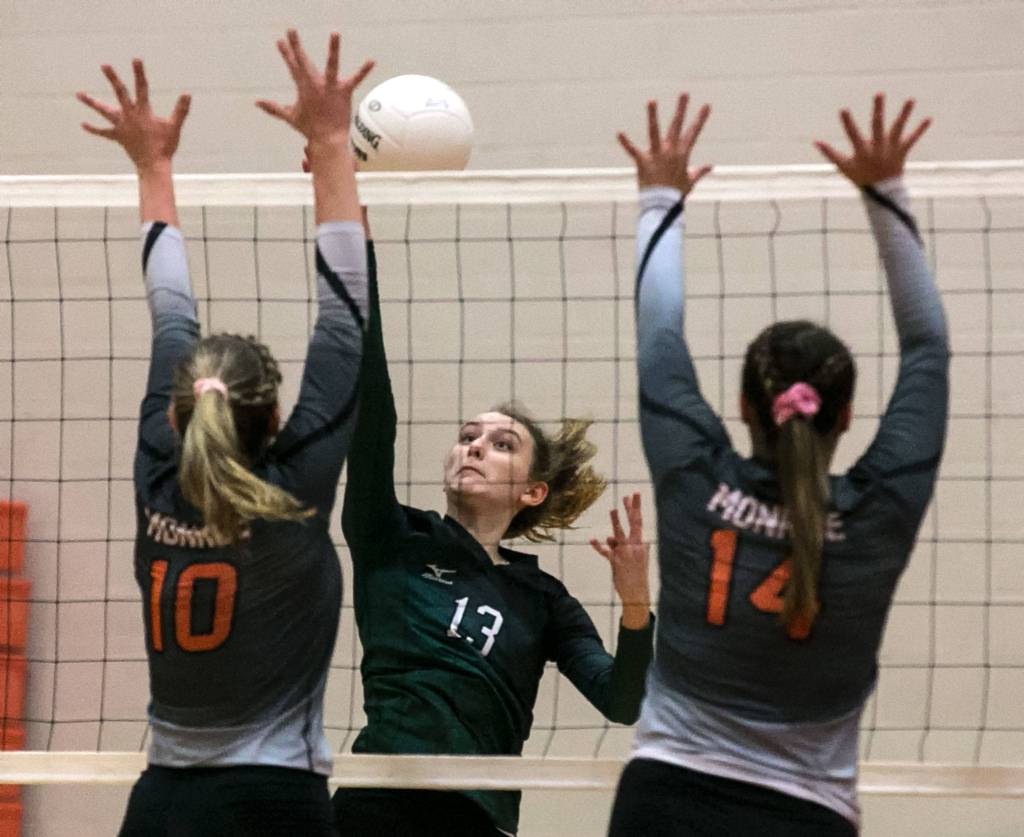 Jacksons Ainsley Johanson attempts a kill with Monroes Tatum McGovern (left) and Sophia Barber blocking at Monroe High School on Oct. 9. (Kevin Clark / The Herald)