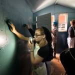 Snohomish High School student Hailey Knie uses her cellphone Monday to light up the wall where she is blending colors of paint in a tiny home at the school. The home was built by classmates and painted by students from the Art Honor Society, and will be used to house the homeless in Seattle. (Andy Bronson / The Herald)