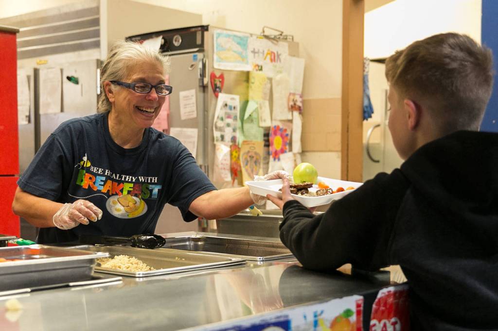 Kathy Baxter (left) serves a meal Wednesday afternoon at Shoultes Elementary School in Marysville. (Kevin Clark / The Herald)