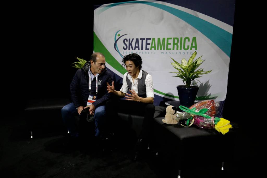 Nathan Chen talks to his coach while waiting for his score in the mens short program at the 2018 Skate America competition Friday at Angel of the Winds Arena in Everett. (Andy Bronson / The Herald)