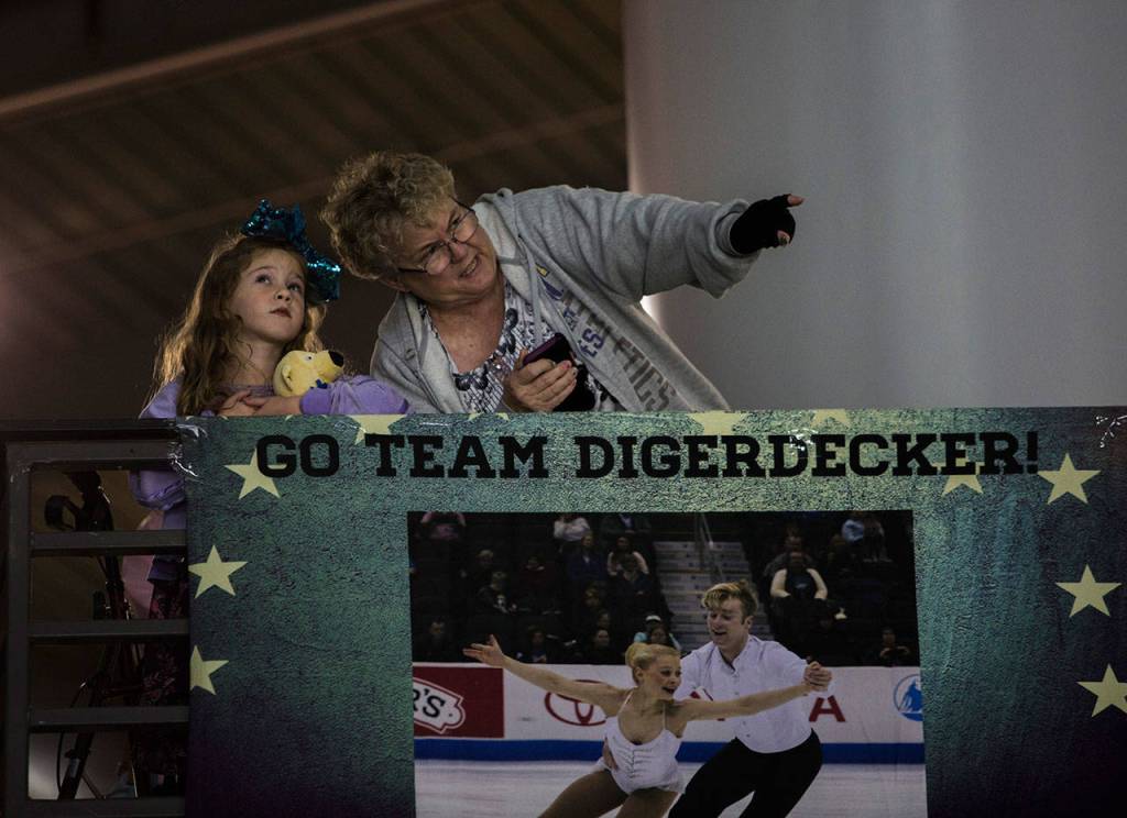 Two spectators watch the pairs warm up before the start of the pairs free skating program at the 2018 Skate America competition on Saturday at Angel of the Winds Arena in Everett. (Olivia Vanni / The Herald)