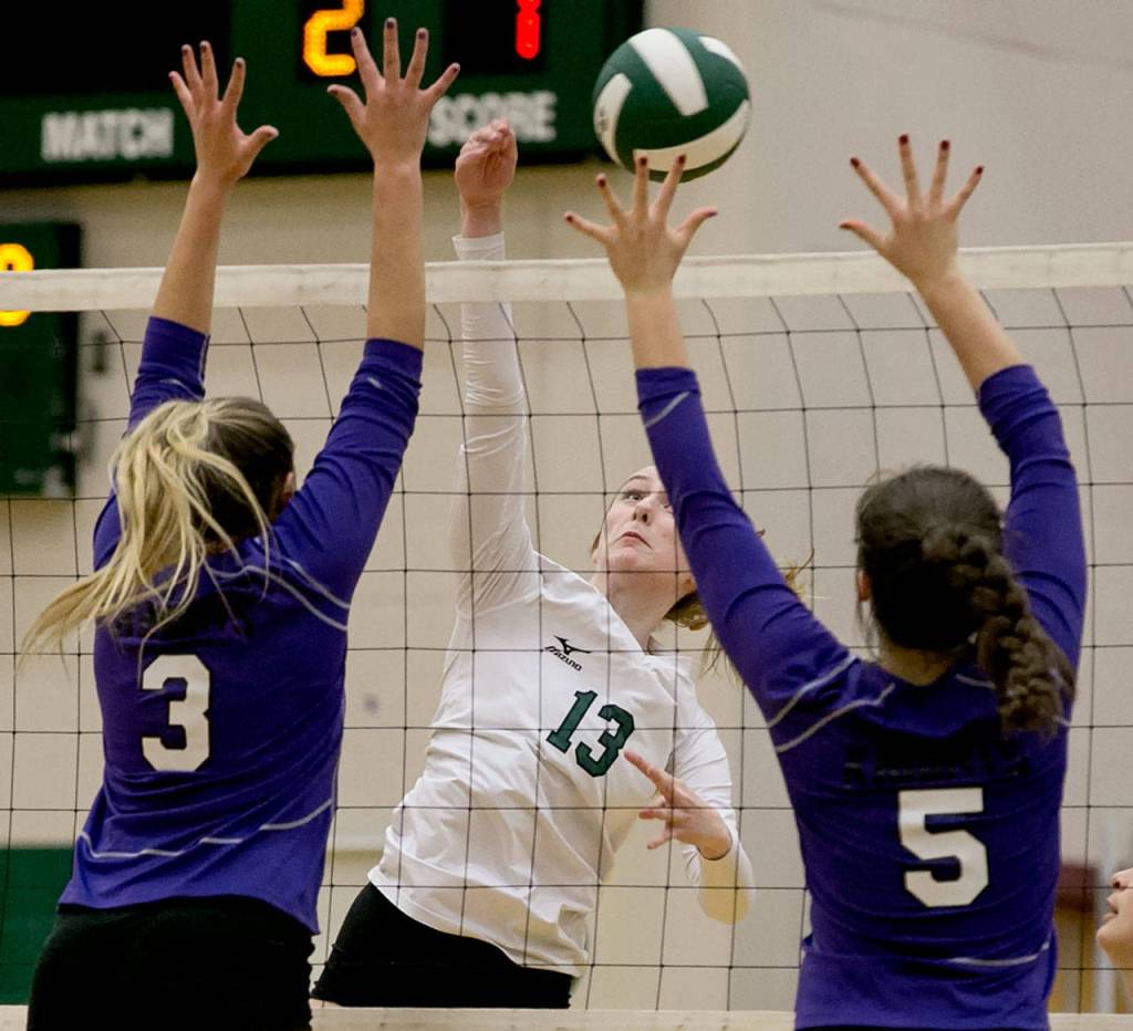 Jacksons Ainsley Johanson (center) hits a ball at the net as Kamiaks Hannah Knutt (left) and Grace Forster (right) leap to make the block during a Wesco 4A match Tuesday at Jackson High School in Mill Creek. (Kevin Clark / The Herald)