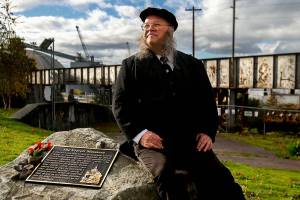 Seated next to the Everett Massacre plaque and dressed with a vintage look, history buff Christopher Summit talks about the events that took place Nov. 5, 1916, from a little different perspective. (Dan Bates / The Herald)