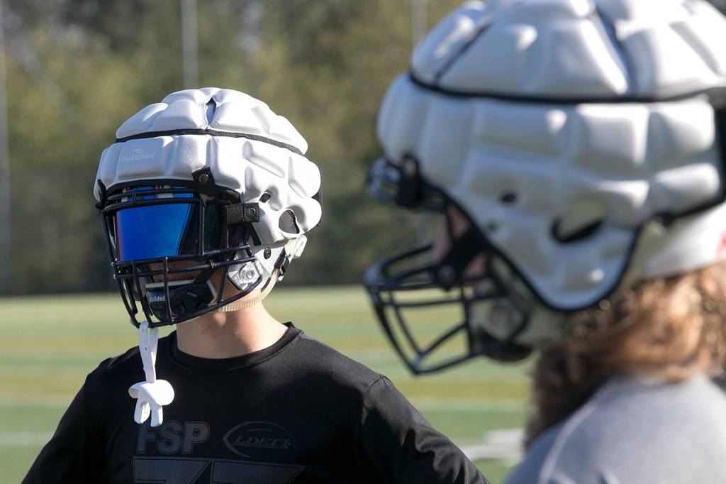 A face mask adds to the alien look as a pair of football players wear Guardian Caps on their helmets during practice at Glacier Peak High School in Snohomish on Oct. 4. (Kevin Clark / The Herald)