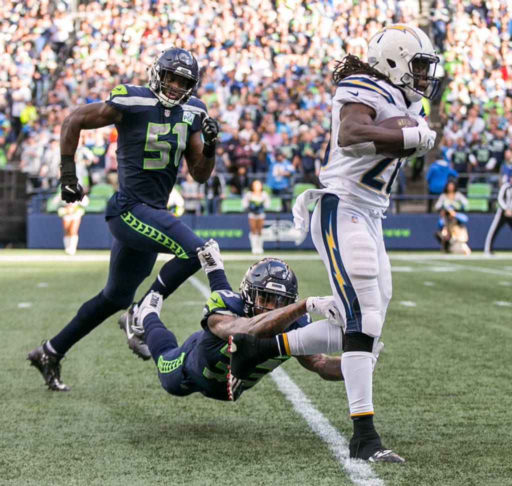 Chargers running back Melvin Gordon III races to avoid Seahawks safety Tedric Thompson (bottom) and Seahawks linebacker Barkevious Mingo Sunday afternoon at CenturyLink Field in Seattle on November 4, 2018. Chargers won 25-17. (Kevin Clark / The Herald)