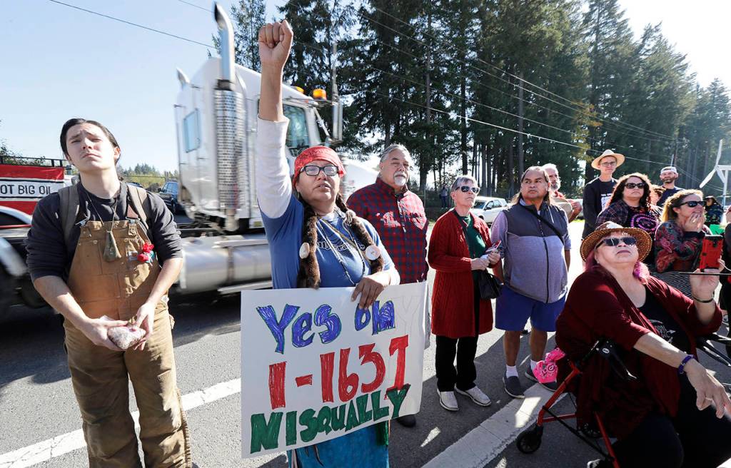 In this Oct. 17 photo, a supporter of Initiative 1631 holds a sign referencing the Nisqually Indian Tribe during a rally supporting I-1631. (AP Photo/Ted S. Warren, File)