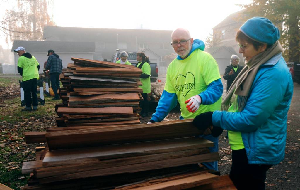 Snohomish Carnegie Foundation Board Members Mac Bates (left) and Clara Granger search for the flattest of cedar shingles to be used as they and other foundation members tackle the job of replacing the shelter roof over the 1940 Lervick log that has been on display in front of the Carnegie library building on Saturday. (Doug Ramsay / For The Herald)