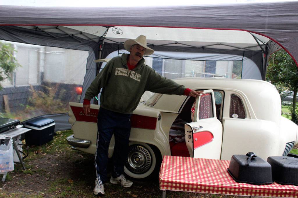 John Norris stands beside Miss Piggy, a camping trailer built from many spare parts of cars, trucks and motorcycles. It was assembled by Brian Woods of British Columbia. (Patricia Guthrie/Whidbey News Group)