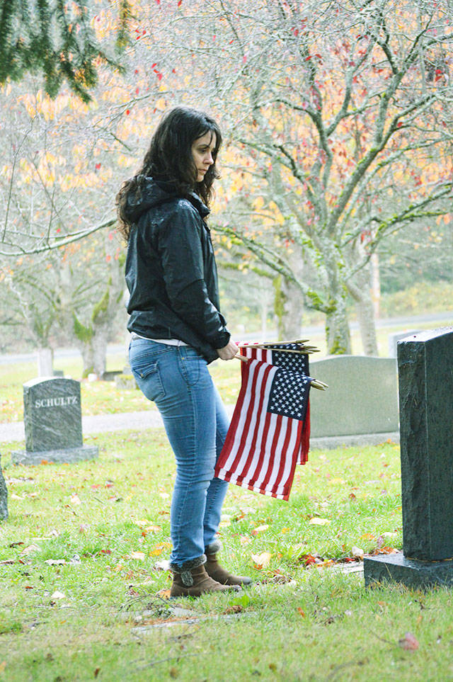 Andrea Kunze looks for gravestones belong to veterans to place a flag near. She and other volunteers participated in the annual event held by the Whidbey Island Military Officers Association to honor fallen service members Saturday morning at Maple Leaf Cemetery in Oak Harbor. (Laura Guido/Whidbey News-Times)