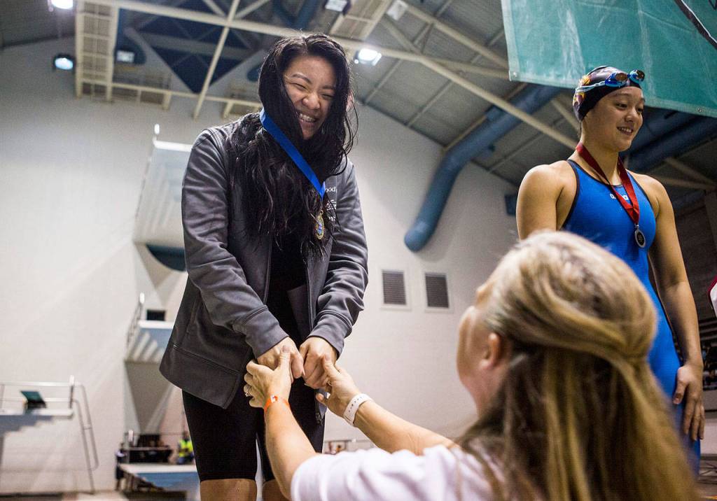 Stanwood junior Jetlynn Hau smiles after receiving her first-place medal after winning the breaststroke at the 3A state swimming and diving championships on Nov. 10, 2018, in Federal Way. Hau finished with a time of 1:03.97 in the event to capture her first state title. (Olivia Vanni / The Herald)
