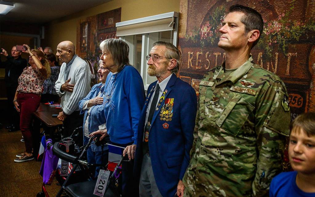 At a Lynnwood care facility Nov. 14, residents, guests and family gather to honor Peter Bellecy, 96, as he recieves a French Legion of Honor medal. Waiting to speak at the presentation ceremony (blue jacket and tie) are Donald Wischmann, quartermaster of Veterans of Foreign Wars Post 2100, and (in camo) Washington Air National Guard Col. Andrew Todd. (Dan Bates / The Herald)