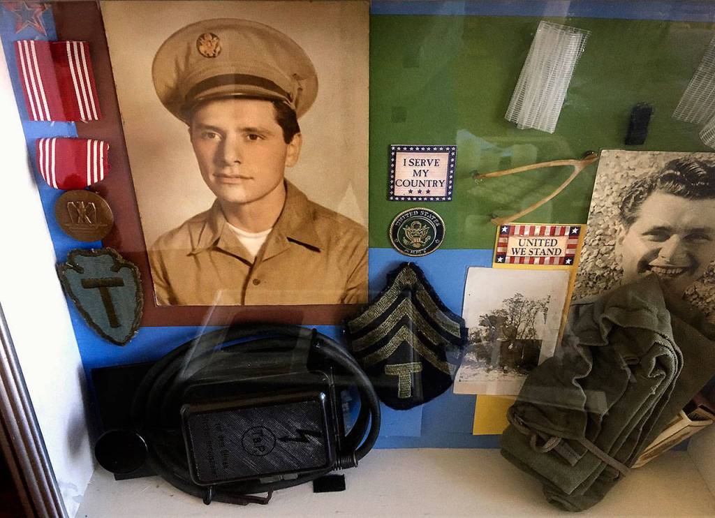 Photos and other items from Peter Bellecys young adulthood more than 70 years back peek from a glass-covered display.