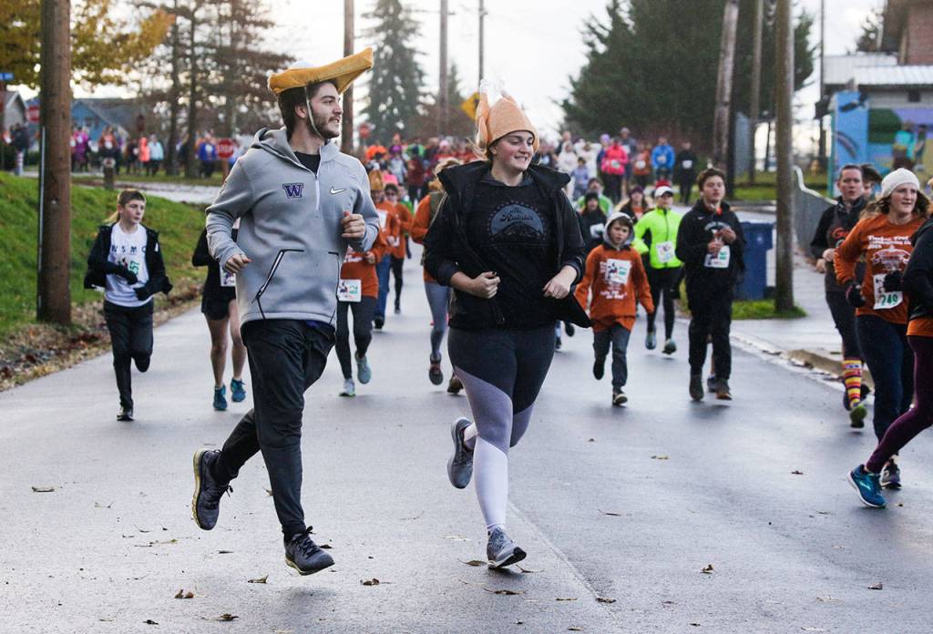 Danielle Guenther, of Bothell, runs with her husky Rhodey at the Turkey Trot 5K on Thursday in Arlington. (Andy Bronson / The Herald)                                 A couple sports pumpkin pie and turkey hats as they run in the Turkey Trot 5K on Thursday in Arlington. (Andy Bronson / The Herald)                                A couple sports pumpkin pie and turkey hats as they run in the Turkey Trot 5K on Thursday in Arlington. (Andy Bronson / The Herald)