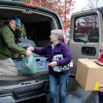 Tony Aguilar arranges donations handed to him by Jean Beers (center) and Norma Hansson. (Patricia Guthrie / Whidbey News Group)