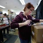 Owner Lacie Marsh-Carroll tapes up a box of candles at Malicious Women Candle Co. on Tuesday in Lake Stevens. At left, Samantha Cofer, sorts and packs candles for an order. (Andy Bronson / The Herald)