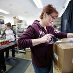 Owner Lacie Marsh-Carroll tapes up a box of candles at Malicious Women Candle Co. on Tuesday in Lake Stevens. At left, Samantha Cofer, sorts and packs candles for an order. (Andy Bronson / The Herald)
