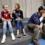 Sporting opposing team gear, Lauren Rice and Avery Kirkman (right) enjoy chatting together as Dutch Hill Elementary held an Apple Cup-themed Dads n Donuts event, with the gym decked out in Cougar and Husky colors, on Nov. 21, 2018, in Snohomish. (Andy Bronson / The Herald)
